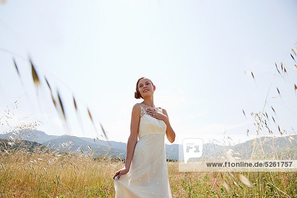 Bride wearing wedding dress alone in field