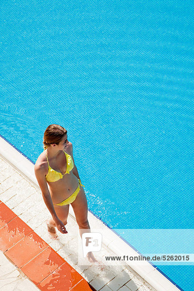 Young woman walking by poolside
