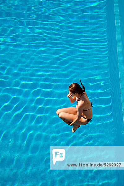 Young woman jumping into swimming pool