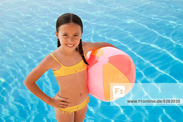 Girl with beach ball by swimming pool  portrait