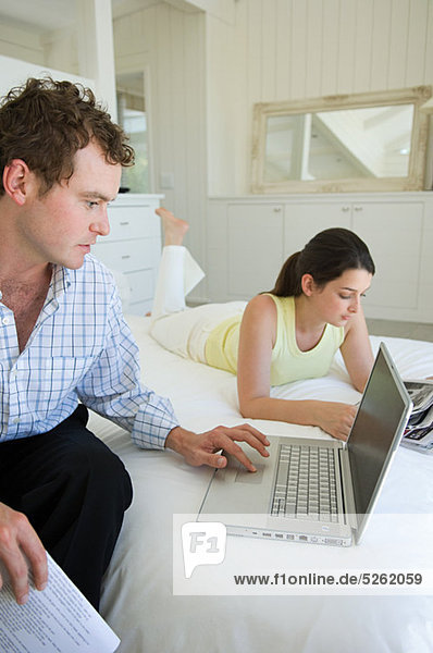 Couple on bed  man using laptop