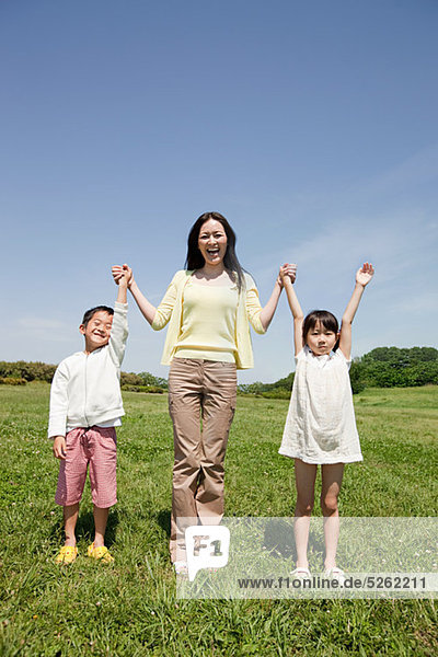 Mother with two children in field with arms up
