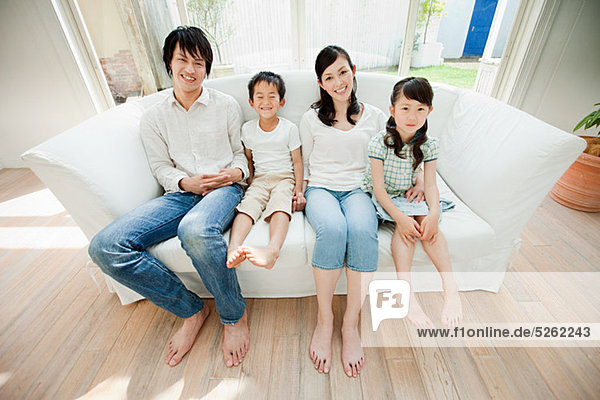 Familie mit zwei Kindern auf Sofa  Porträt