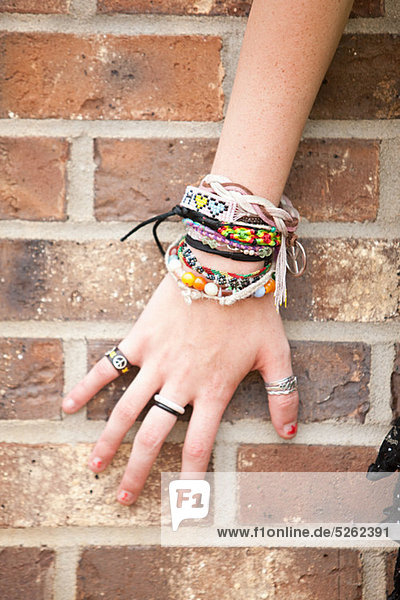 Woman's hand with bracelets by brick wall