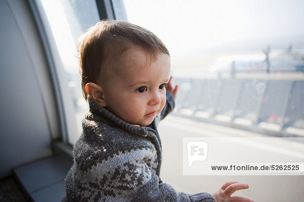 Junge berührt Flughafenfenster