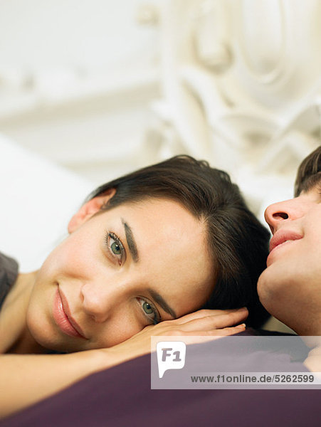 Young couple lying in bed  woman's head on man's shoulder
