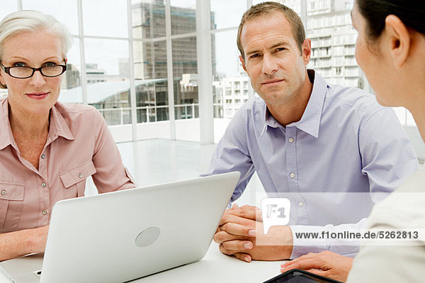 Three businesspeople meeting in office using laptop
