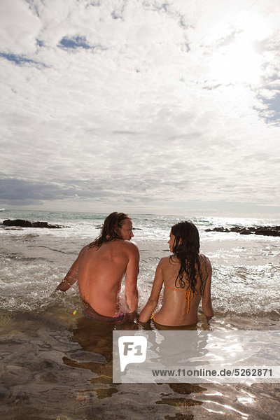 Couple sitting im Meer  Rückansicht