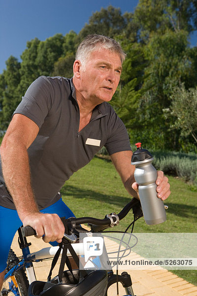 Senior male cyclist holding water bottle