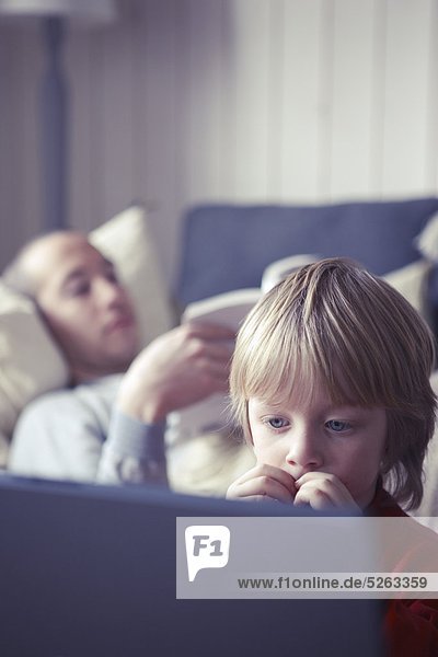 Boy looking at Computer-Bildschirm  Mann im Hintergrund