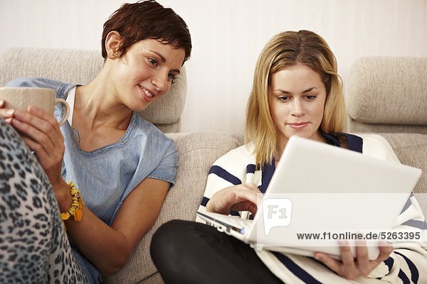 Zwei Frauen sitzen auf dem Sofa und mit laptop