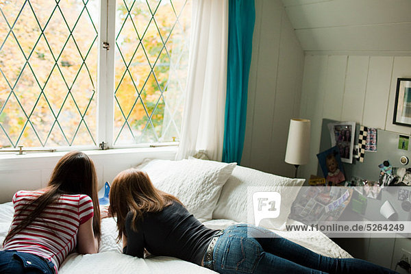 Two teenage girls lying on bed