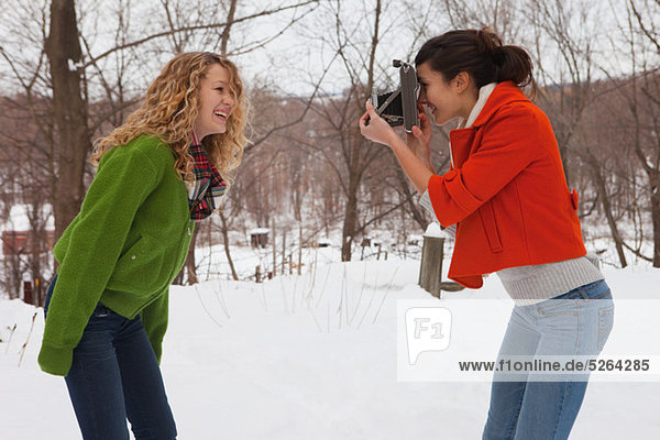 Teenager-Mädchen nehmen Foto von Freund im Schnee