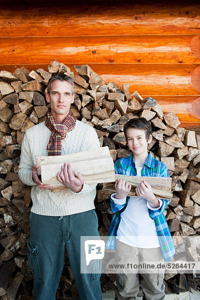 Father and son holding logs  portrait
