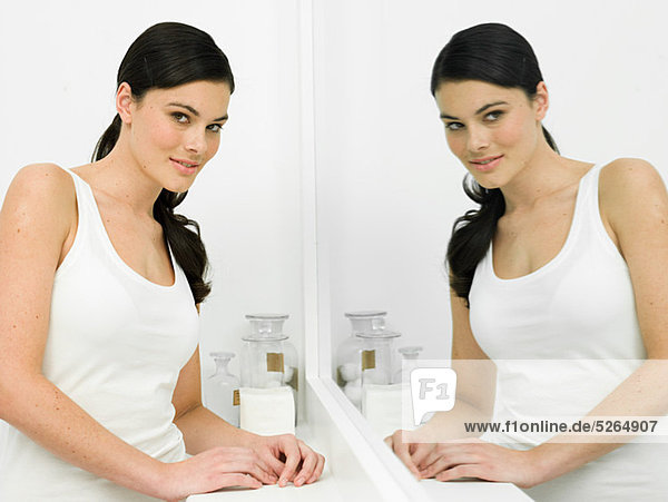 Reflection of young woman in bathroom mirror