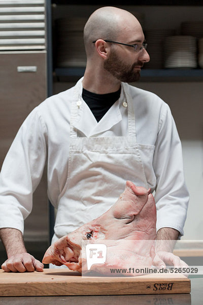 Butcher preparing with head of pig