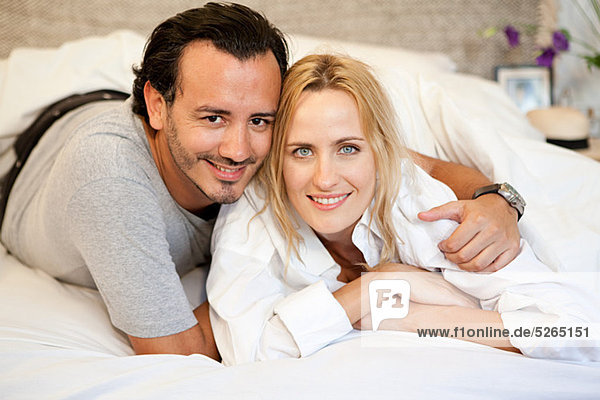 Couple lying on bed and looking at camera