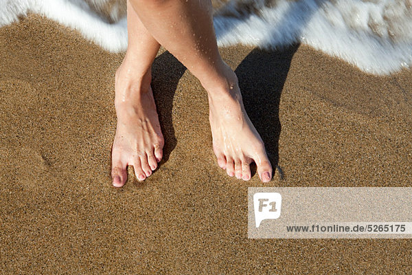 Woman's bare feet on sandy beach