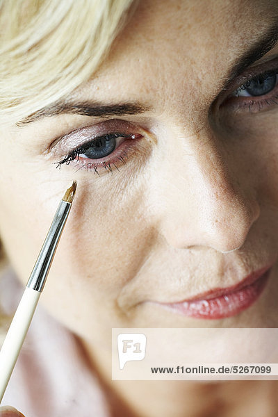Nahaufnahme der Reife Frau Anwendung Concealer unter Auge