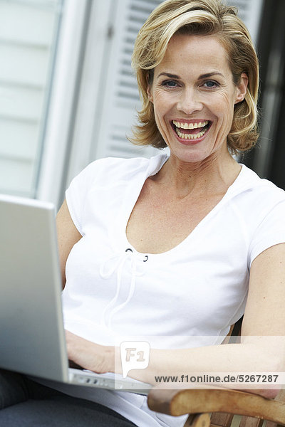 Reife Frau auf ihre Arbeiten fort ihr Laptop beachouse