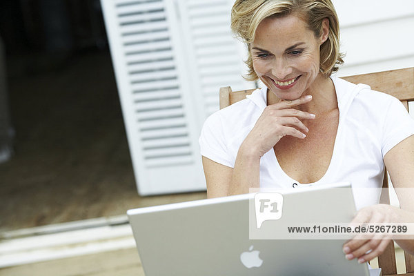Reife Frau auf ihre Arbeiten fort ihr Laptop beachouse