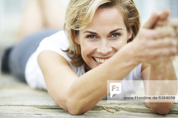 Fröhlich Reife Woman lying on Deck spielen mit sand