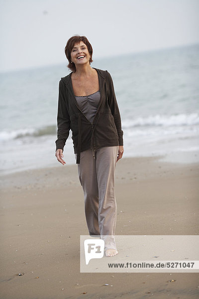 Reife Frau zu Fuß am Strand