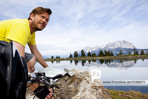 Man with mountainbike at a rock orientating himself