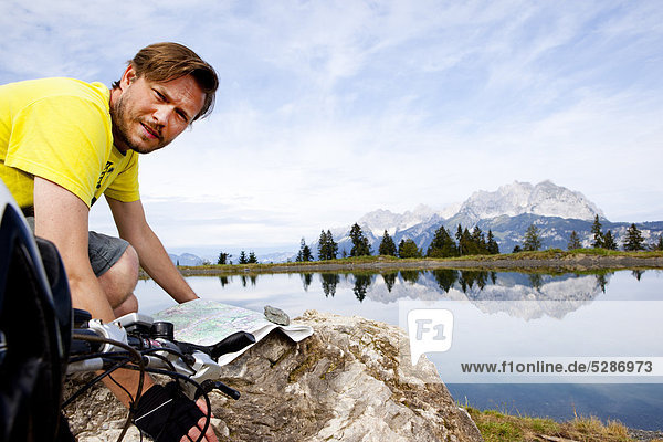 Man with mountainbike at a rock orientating himself