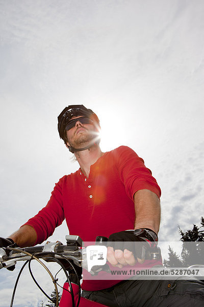 Mann in rotem Langarmshirt auf einem Mountainbike