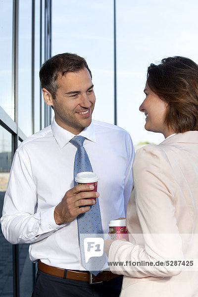 Geschäftsmann und Geschäftsfrau mit Coffee to Go unterhalten sich