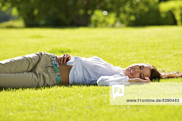 Beautiful brunette girl lying on the grass