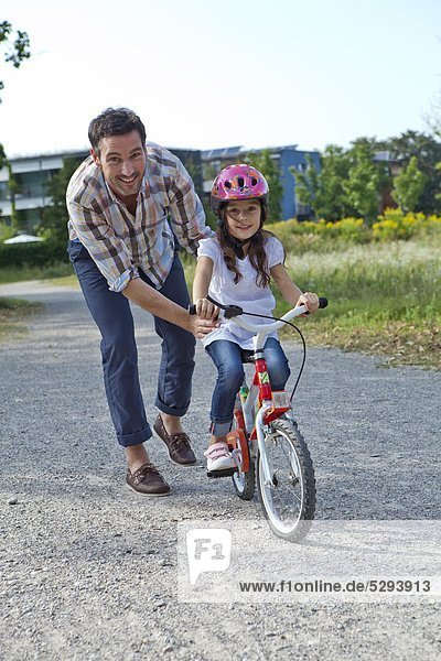 Father holding daughter on bike outdoors