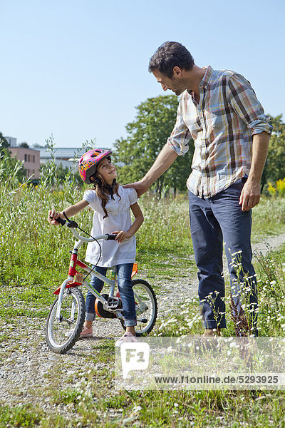 Vater und Tochter auf Fahrrad im Freien