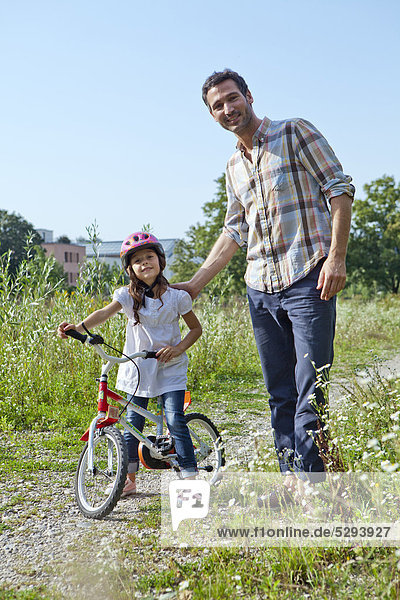 Vater und Tochter auf Fahrrad im Freien