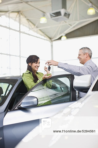 Autoverkäufer übergibt Schlüssel an Kunden