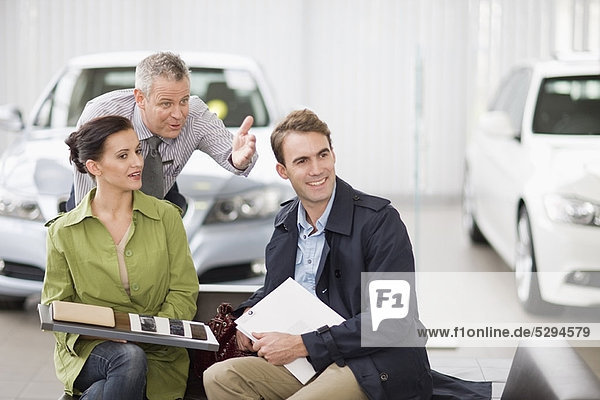 Autoverkäufer im Gespräch mit einem Paar