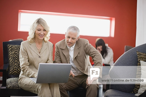 Business people using laptop in lounge