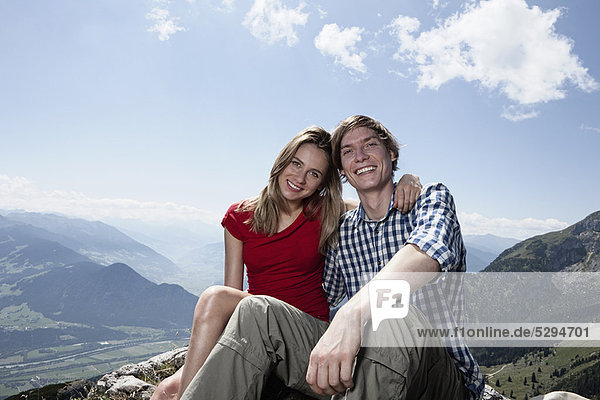 Smiling couple sitting on hilltop