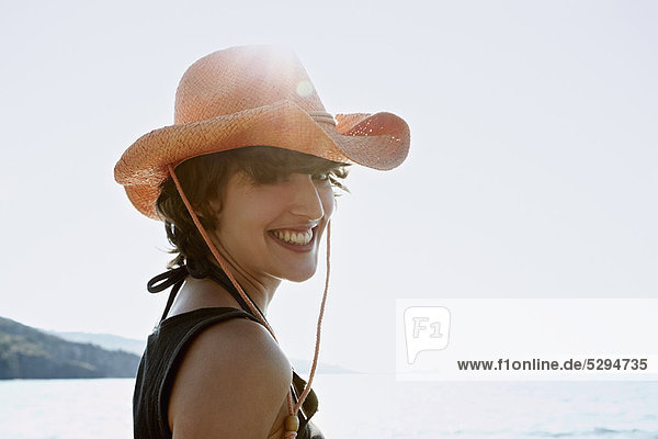 Lächelnde Frau mit Sonnenhut am Strand