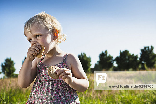Toddler girl eating crackers outdoors