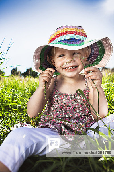 Toddler girl wearing sunhat in grass