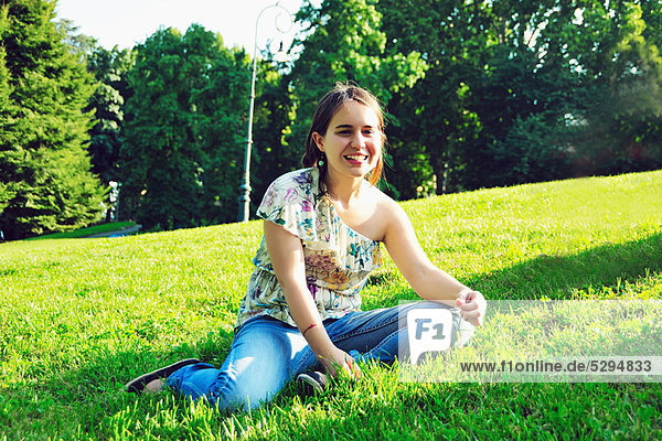 Woman sitting in grass in park