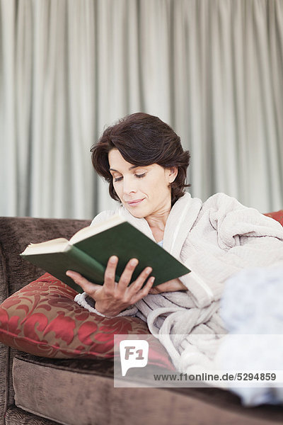 Woman in bathrobe reading book