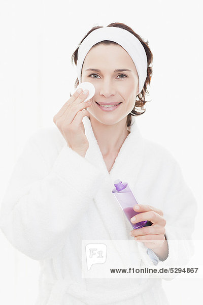 Woman in bathrobe cleansing her face