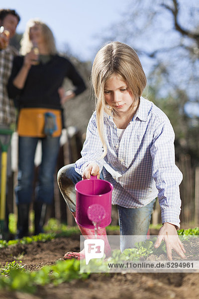 Mädchen gießen Pflanzen im Garten