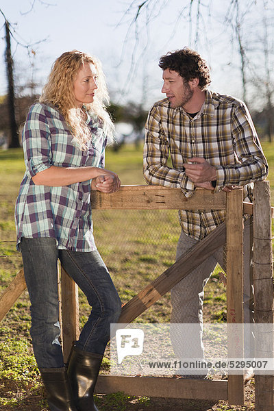Couple talking on wooden fence outdoors