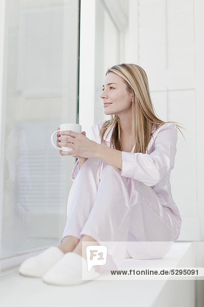 Frau bei einer Tasse Kaffee im Schlafanzug