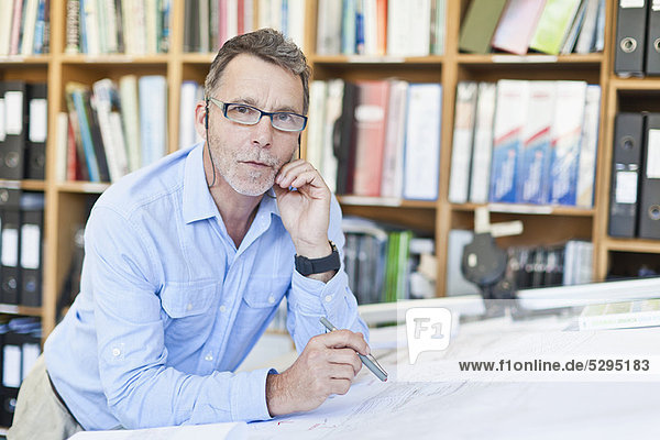 Businessman reading blueprints in office