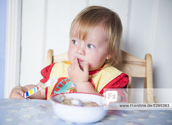 Kleinkind Mädchen im Lätzchen beim Essen am Tisch
